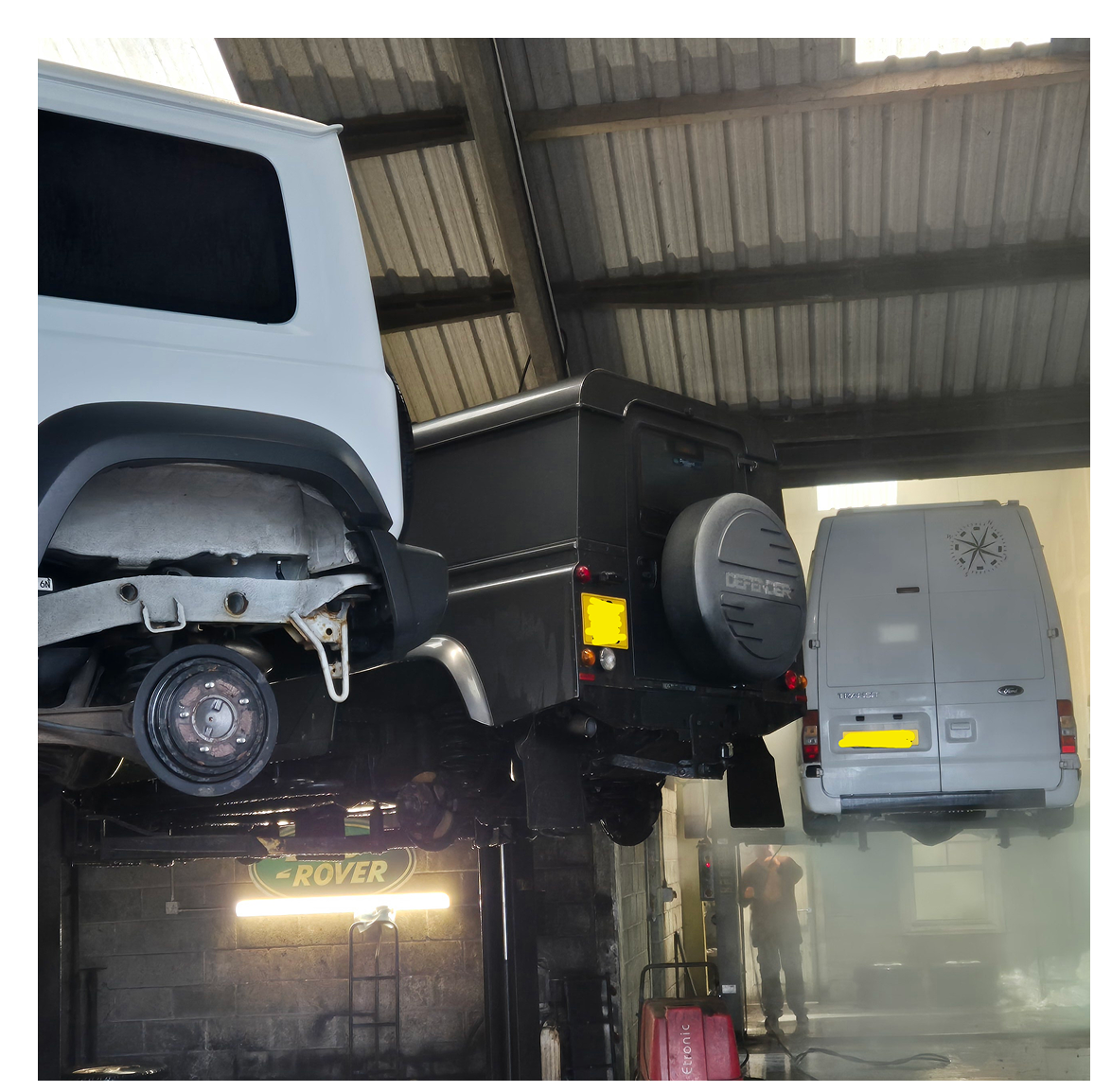 Vehicles lifted inside automotive repair garage